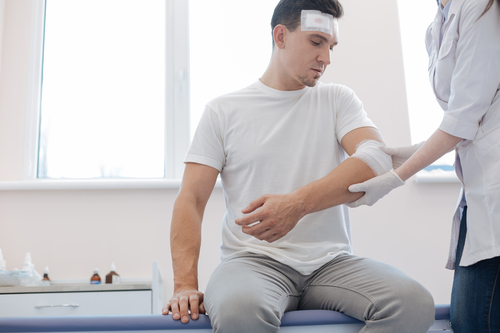 What You Should Do If You Are Hurt At Work - Cheerless wounded man looking at his injury