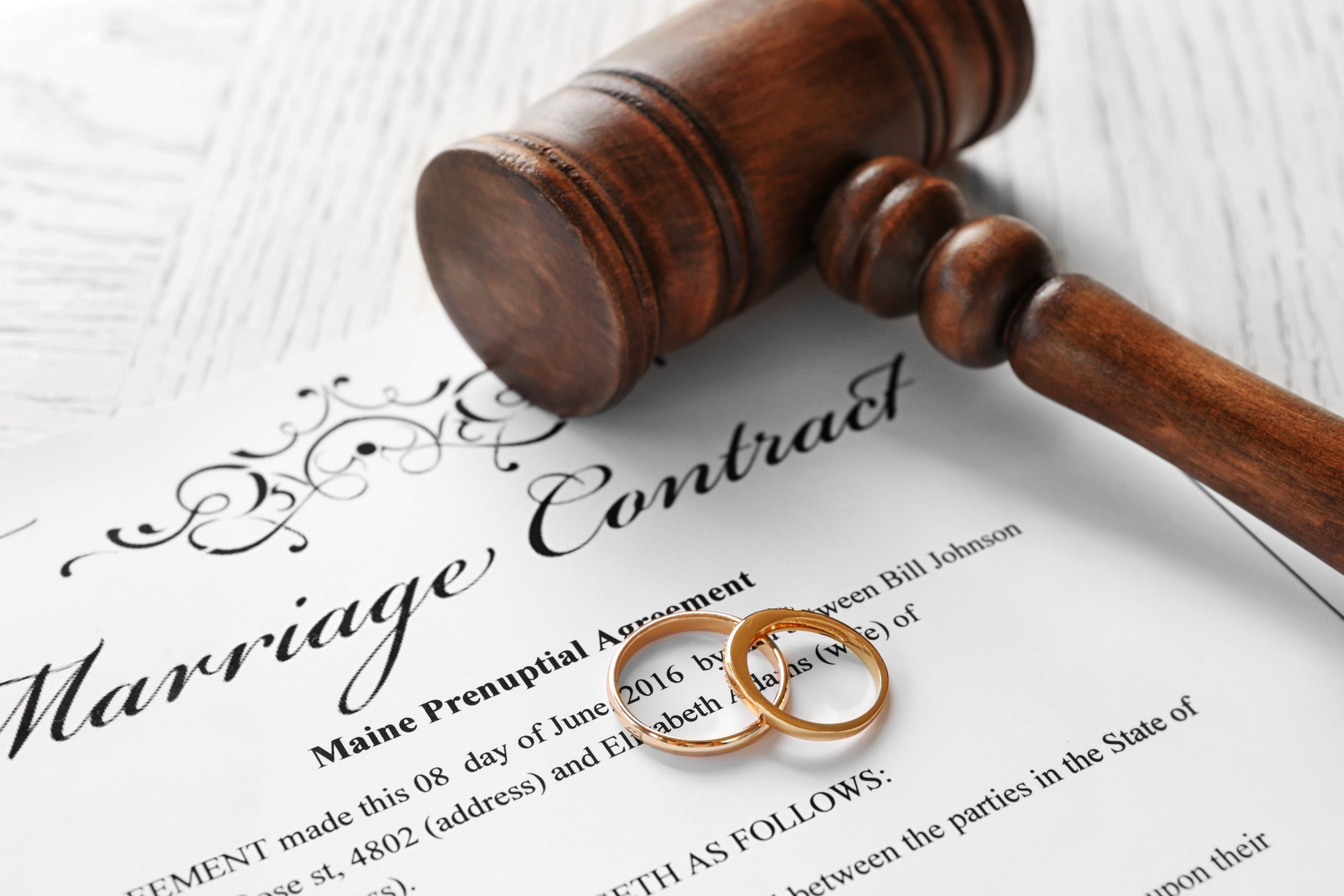 What To Know When Initiating Divorce - Golden wedding rings with judge gavel on marriage contract, closeup